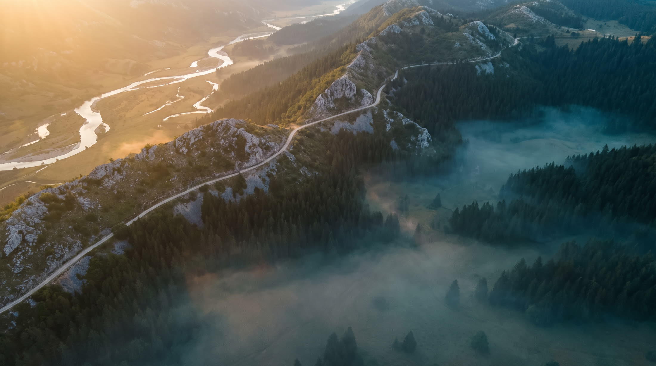 Aerial view at dawn of a road winding between fogged Bosnian ridges